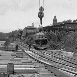 Cableway picking up bucket from tramway on east side. The tramway connected the concrete plant with the base of the tower where materials could be delivered to different parts of the site