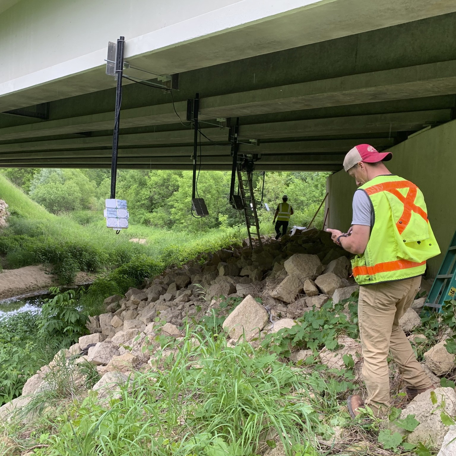 photo of workers installing acoutic devices under bridge