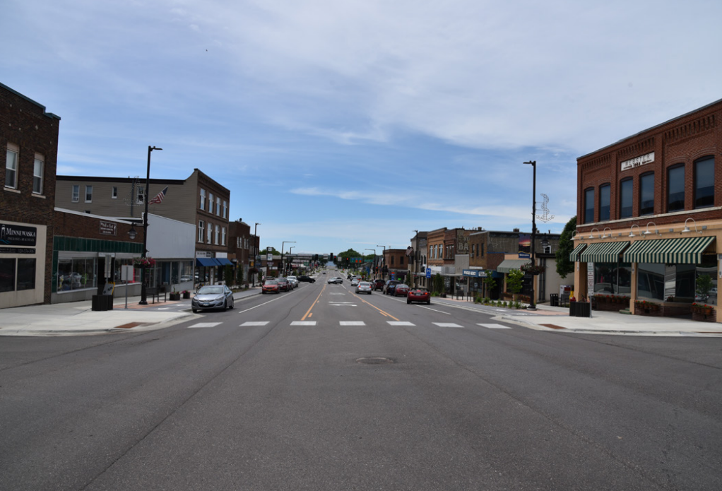 Hwy 28 (Minnesota Ave.) after construction, showing lane reduction to two traffic lanes and a center turn lane, raised cycletrack, bumpouts, and improved crosswalk